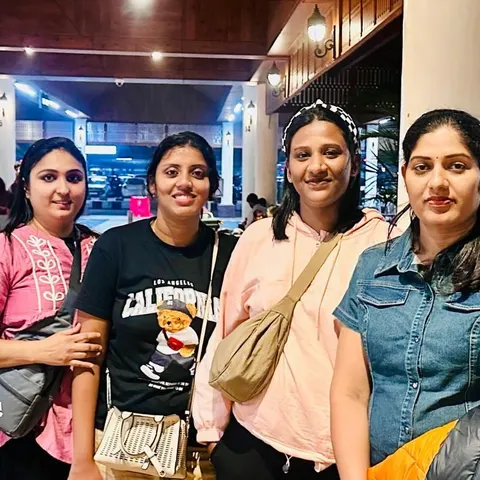 Four women with suitcases outside an airport at night