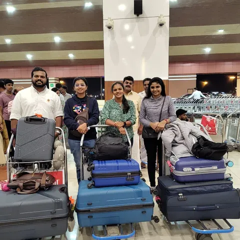 Four travellers with loaded luggage trolleys at an airport