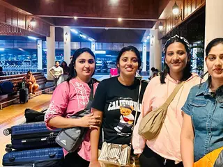 Four women with suitcases outside an airport at night