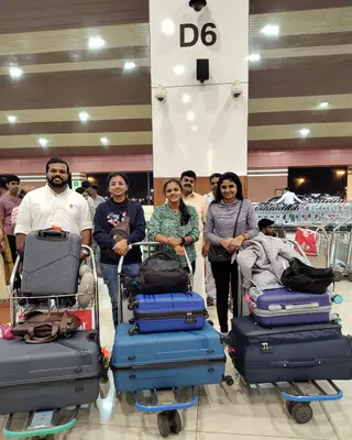Four travellers with loaded luggage trolleys at an airport
